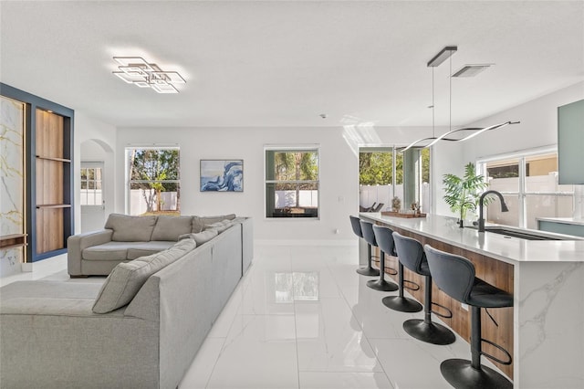 living area with baseboards, visible vents, arched walkways, and marble finish floor