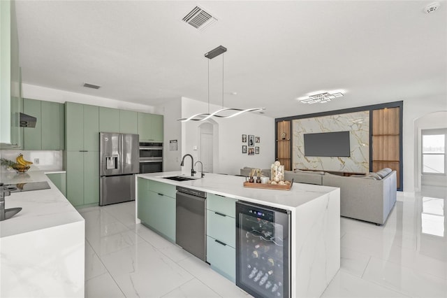 kitchen featuring visible vents, marble finish floor, beverage cooler, a sink, and stainless steel appliances