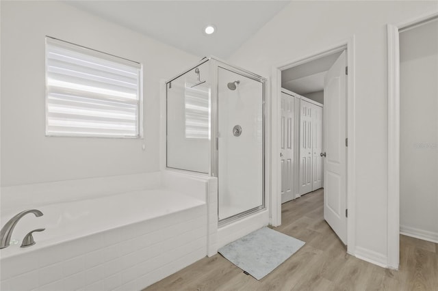 bathroom with recessed lighting, a shower stall, a garden tub, and wood finished floors