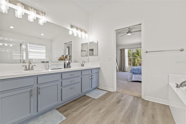 bathroom with double vanity, wood finished floors, ensuite bathroom, and a sink