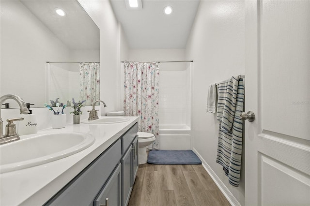 bathroom with toilet, wood finished floors, shower / tub combo with curtain, and a sink