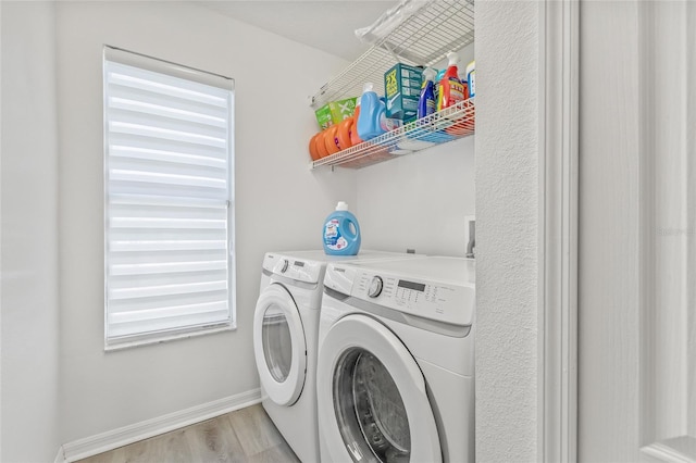 washroom with baseboards, washing machine and dryer, a wealth of natural light, laundry area, and light wood-style floors