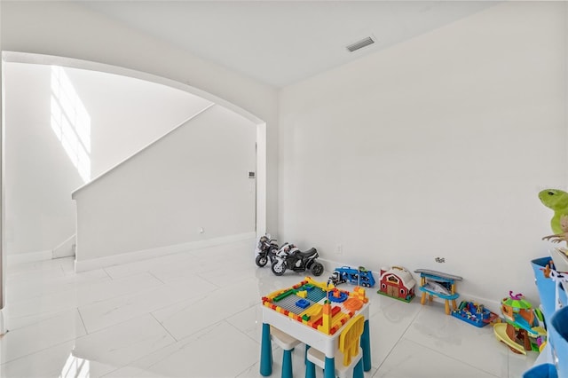 recreation room with arched walkways, visible vents, and baseboards