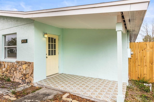 doorway to property with fence and stucco siding