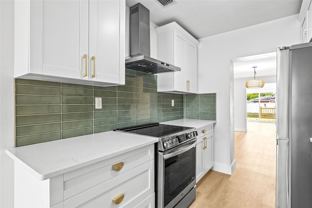 kitchen featuring stainless steel appliances, light wood-style floors, white cabinetry, wall chimney exhaust hood, and backsplash