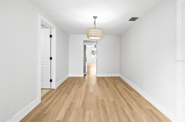 unfurnished dining area featuring light wood-style floors, visible vents, and baseboards