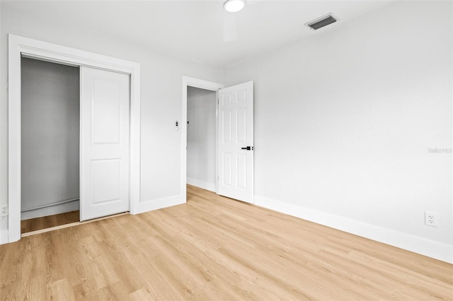 unfurnished bedroom with light wood-style floors, visible vents, a closet, and baseboards