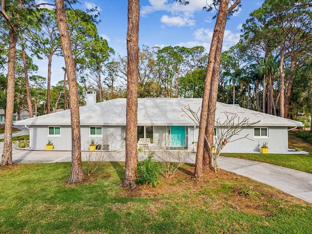 single story home featuring driveway, a chimney, and a front yard