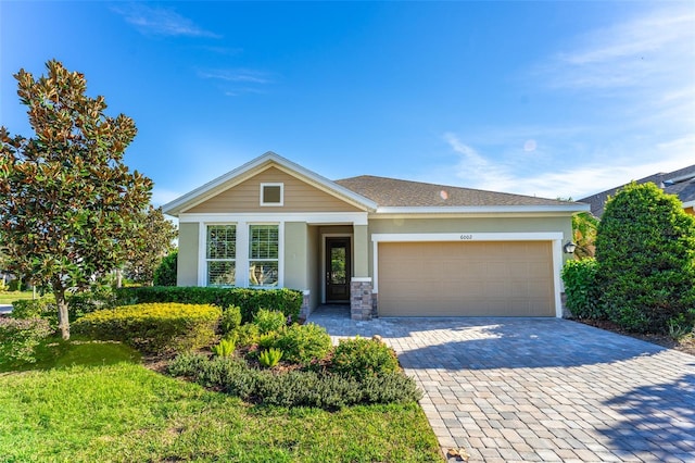 single story home with stone siding, stucco siding, an attached garage, and decorative driveway