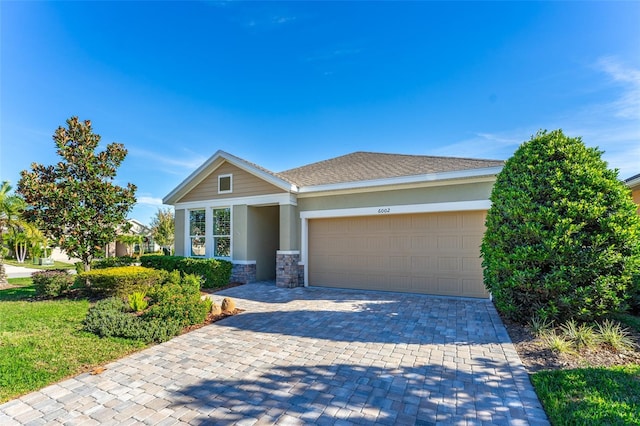 view of front of property featuring roof with shingles, stucco siding, a garage, stone siding, and decorative driveway