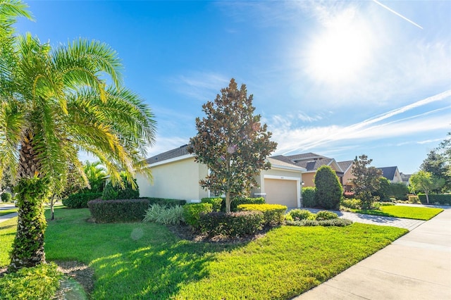 view of side of property featuring an attached garage, a lawn, driveway, and stucco siding