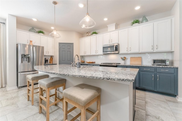 kitchen featuring a breakfast bar area, a sink, appliances with stainless steel finishes, white cabinetry, and backsplash