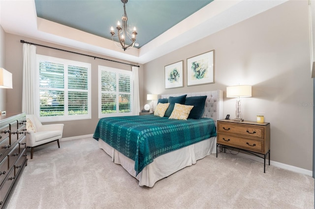 carpeted bedroom with a tray ceiling, baseboards, and a notable chandelier