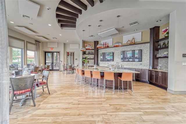 kitchen with visible vents, a breakfast bar, decorative backsplash, and open shelves