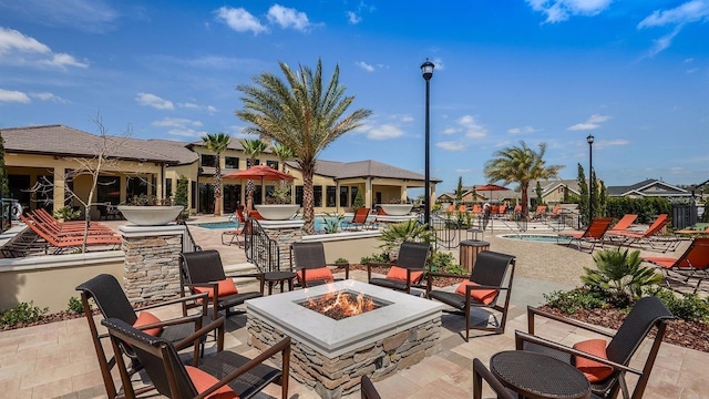 view of patio with a community pool, a hot tub, and an outdoor fire pit