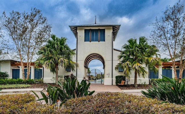 view of front facade with stucco siding and a gate