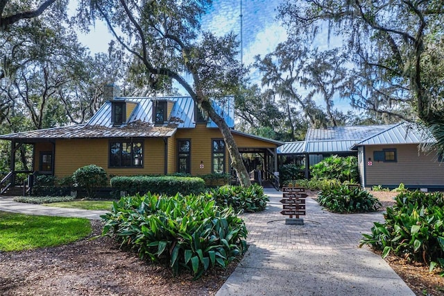 back of house featuring a chimney, metal roof, and a standing seam roof