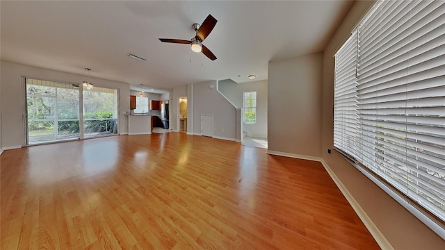 unfurnished living room featuring visible vents, light wood-style flooring, baseboards, and a ceiling fan