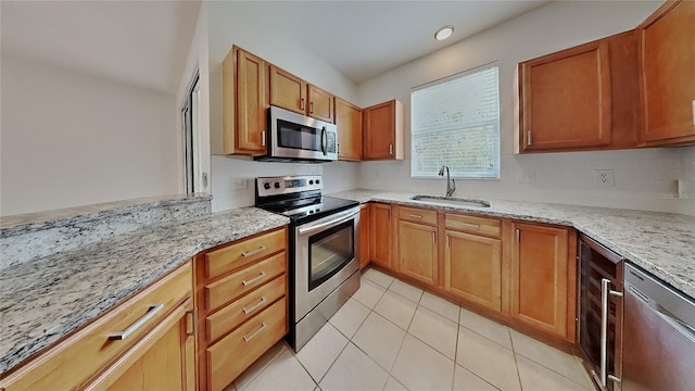 kitchen featuring a sink, stainless steel appliances, light stone countertops, and tasteful backsplash