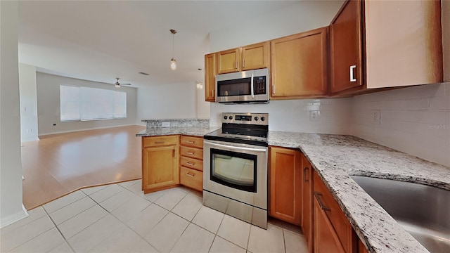 kitchen with a sink, open floor plan, appliances with stainless steel finishes, a peninsula, and decorative backsplash