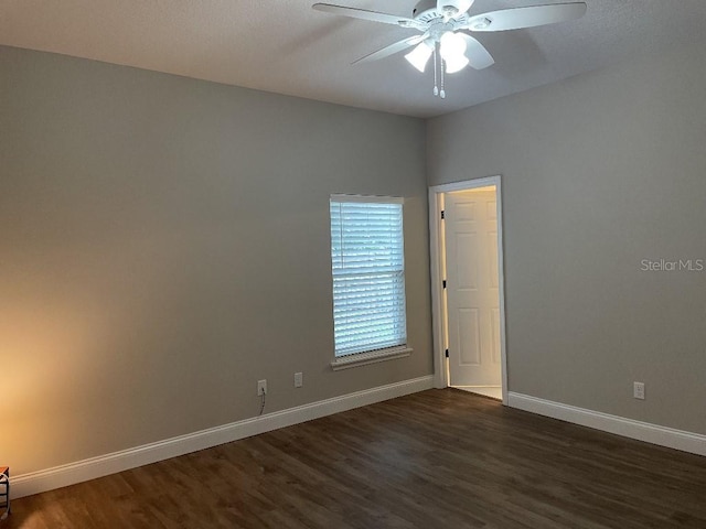 spare room featuring ceiling fan, baseboards, and dark wood finished floors