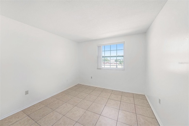 spare room featuring baseboards and a textured ceiling