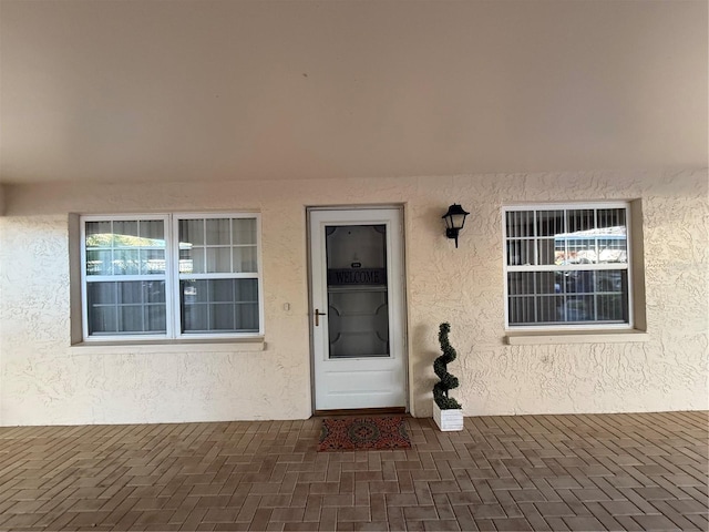 entrance to property featuring a patio and stucco siding