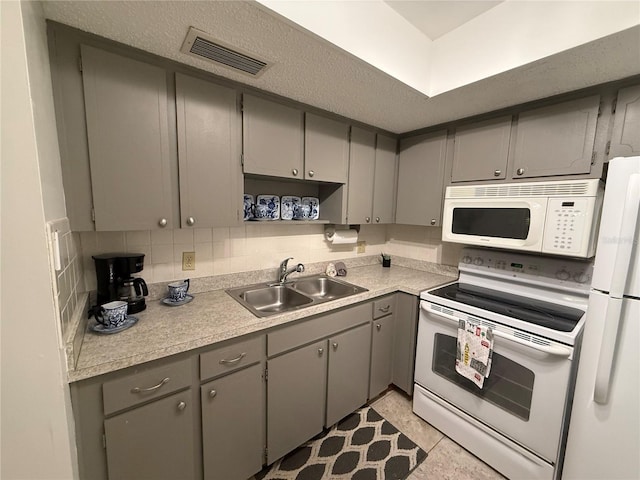 kitchen featuring white appliances, visible vents, gray cabinets, a sink, and tasteful backsplash