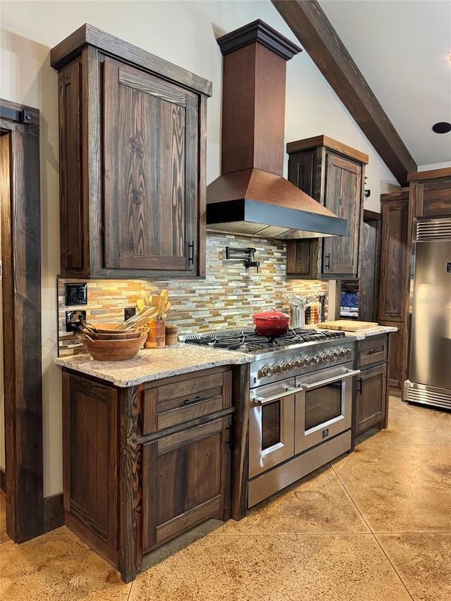 kitchen featuring tasteful backsplash, high end appliances, dark brown cabinetry, and wall chimney range hood