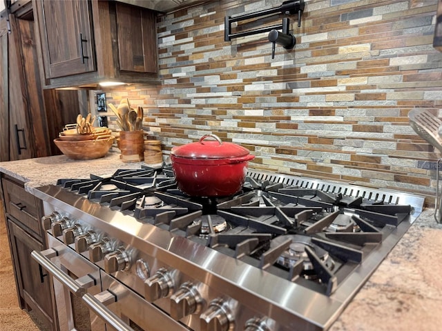 room details featuring decorative backsplash, dark brown cabinets, double oven range, and light stone countertops