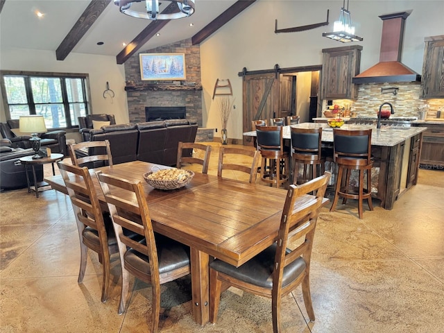 dining area featuring beam ceiling, a fireplace, high vaulted ceiling, and a barn door