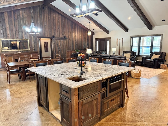 kitchen featuring wooden walls, beamed ceiling, a barn door, an inviting chandelier, and high vaulted ceiling