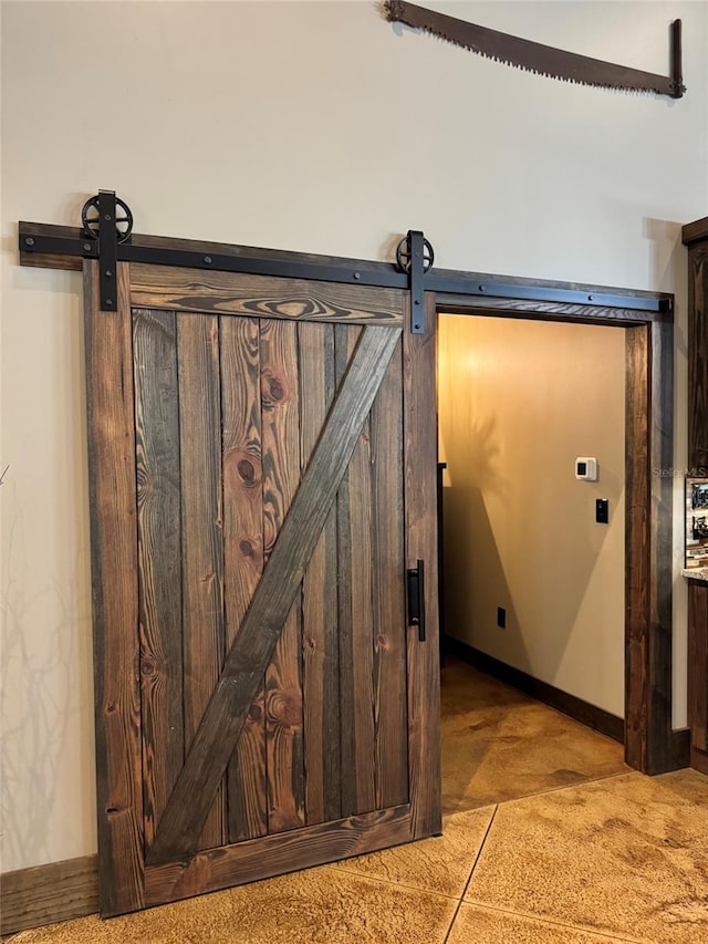 room details featuring a barn door and baseboards