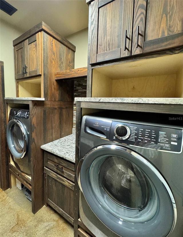 laundry area featuring cabinet space, washer / dryer, and light carpet