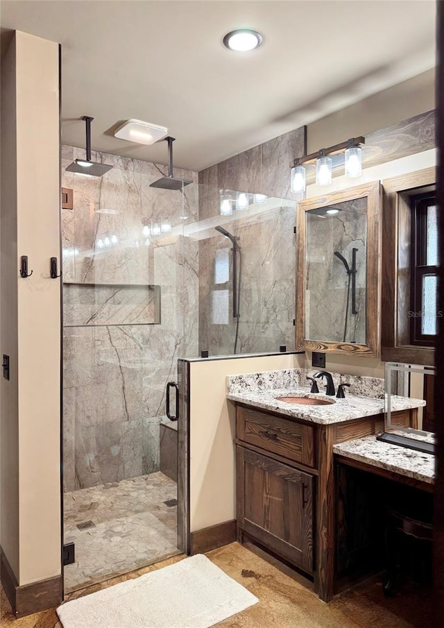 full bathroom with a marble finish shower and vanity