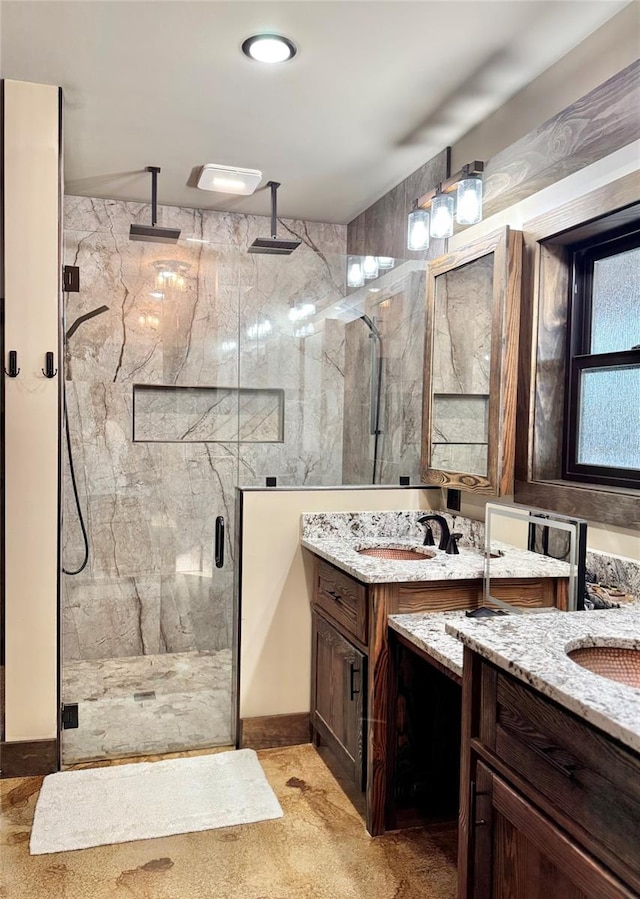 bathroom featuring a sink, a marble finish shower, and two vanities