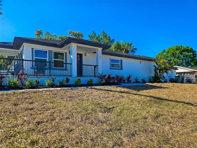 single story home with stucco siding, a porch, and a front yard