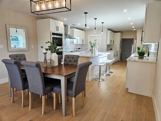 dining room with light wood finished floors, recessed lighting, and baseboards