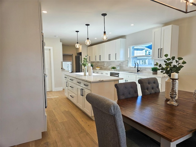 kitchen featuring white cabinets, tasteful backsplash, light wood-type flooring, and a kitchen island