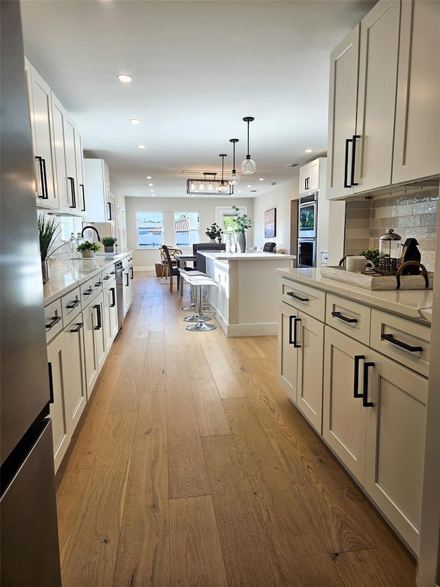 kitchen with light wood finished floors, tasteful backsplash, light countertops, recessed lighting, and appliances with stainless steel finishes