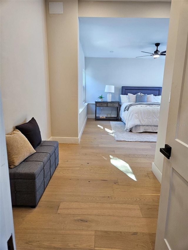 bedroom with a ceiling fan, wood finished floors, and baseboards