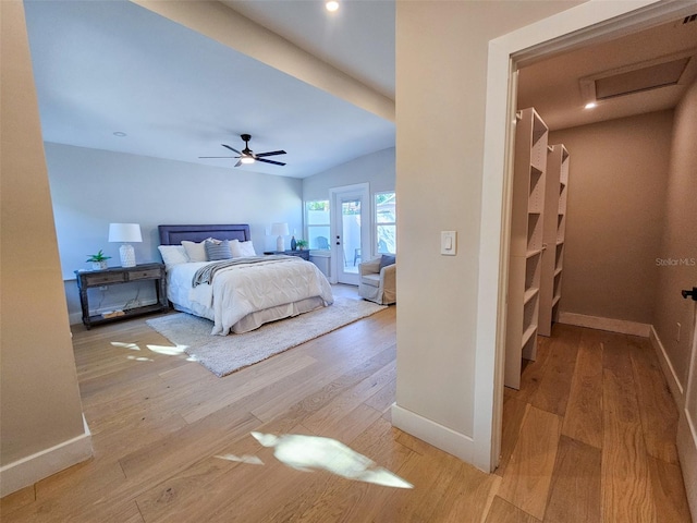 bedroom with attic access, light wood-style floors, and baseboards