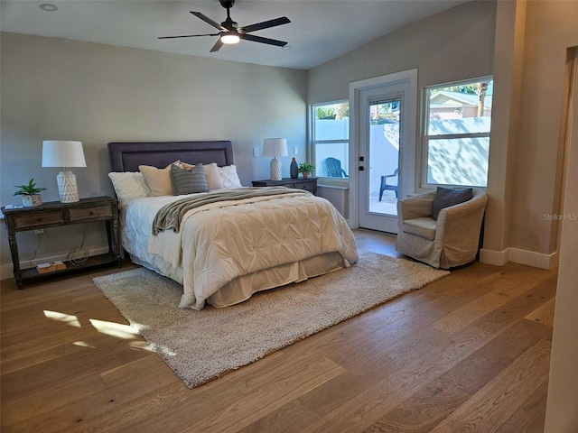 bedroom with a ceiling fan, access to outside, wood-type flooring, baseboards, and vaulted ceiling