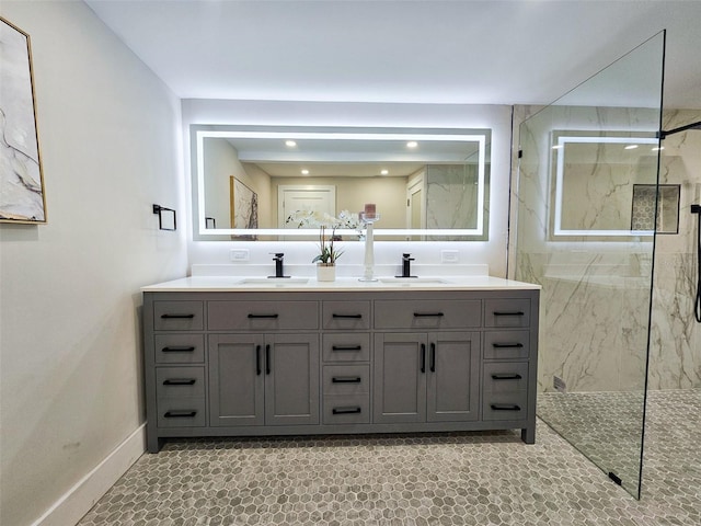 bathroom featuring a sink, a marble finish shower, and double vanity