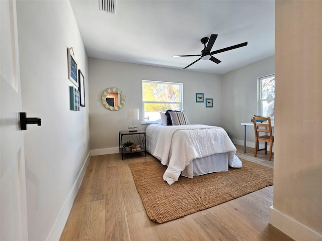 bedroom featuring multiple windows, wood finished floors, visible vents, and baseboards