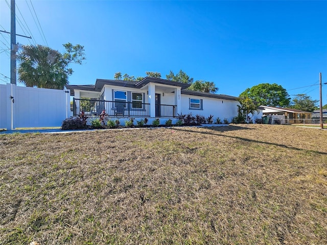 view of front of home with a porch, fence, and a front lawn