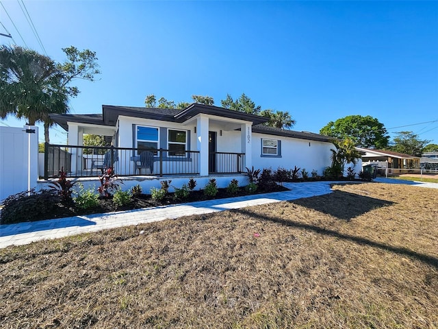 ranch-style house with stucco siding, a porch, and a front yard