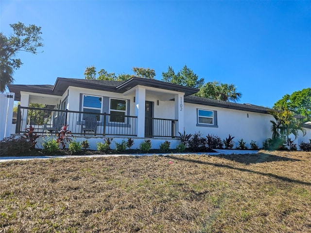 ranch-style house with stucco siding, a porch, and a front yard