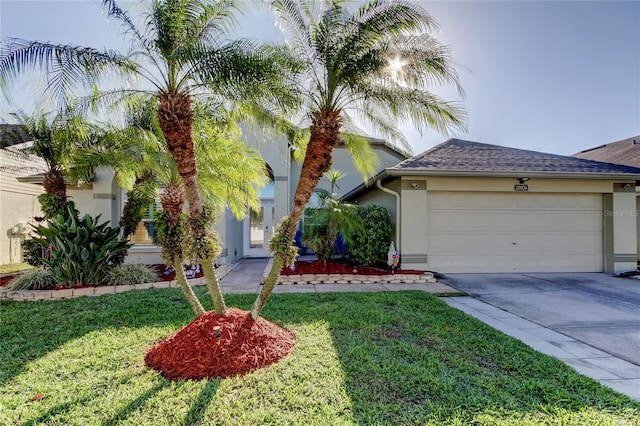 view of front of property with a shingled roof, a front lawn, concrete driveway, stucco siding, and an attached garage