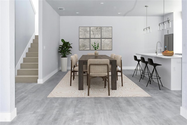 dining area with light wood finished floors, visible vents, stairway, and baseboards